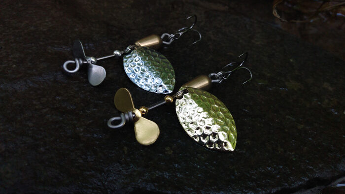Closeup view of silver and gold fishing spinners with a dark background.