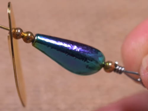 A small inline spinner with a brass-colored blade and blue sinker.