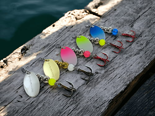 Five Hoffman spinners in different colors. The Hipster Trout Pro Pack pictured against creek water.