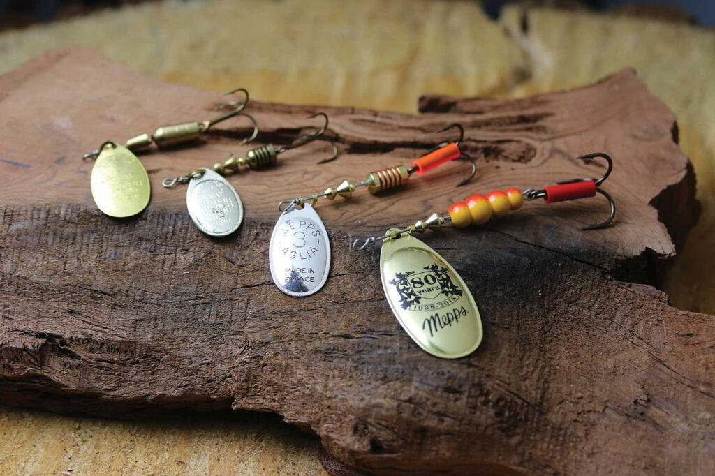 Mepps 80th Anniversary inline spinners photographed on a beautiful slab of wood.